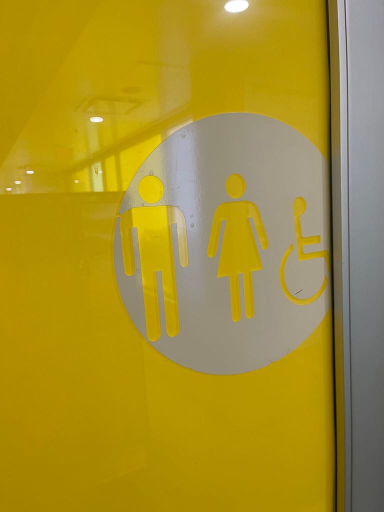 A yellow Extremely heavy bathroom door without a push button opener.