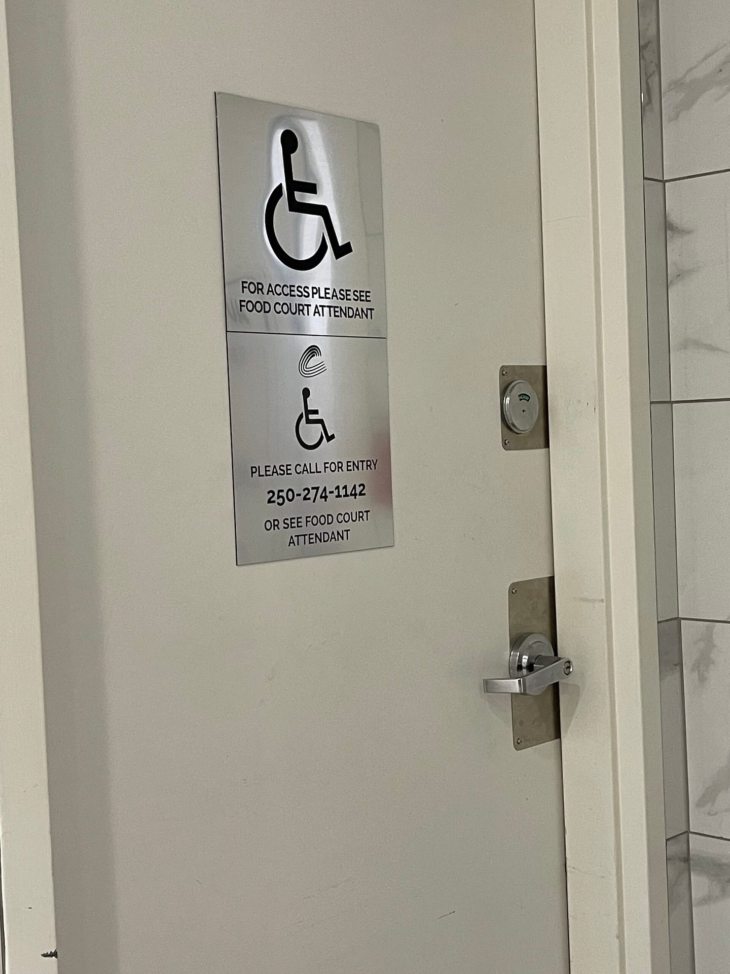 Image of a locked accessible bathroom. SIgnbreads " for access please see food court attendant. Please call 250 -274-11**